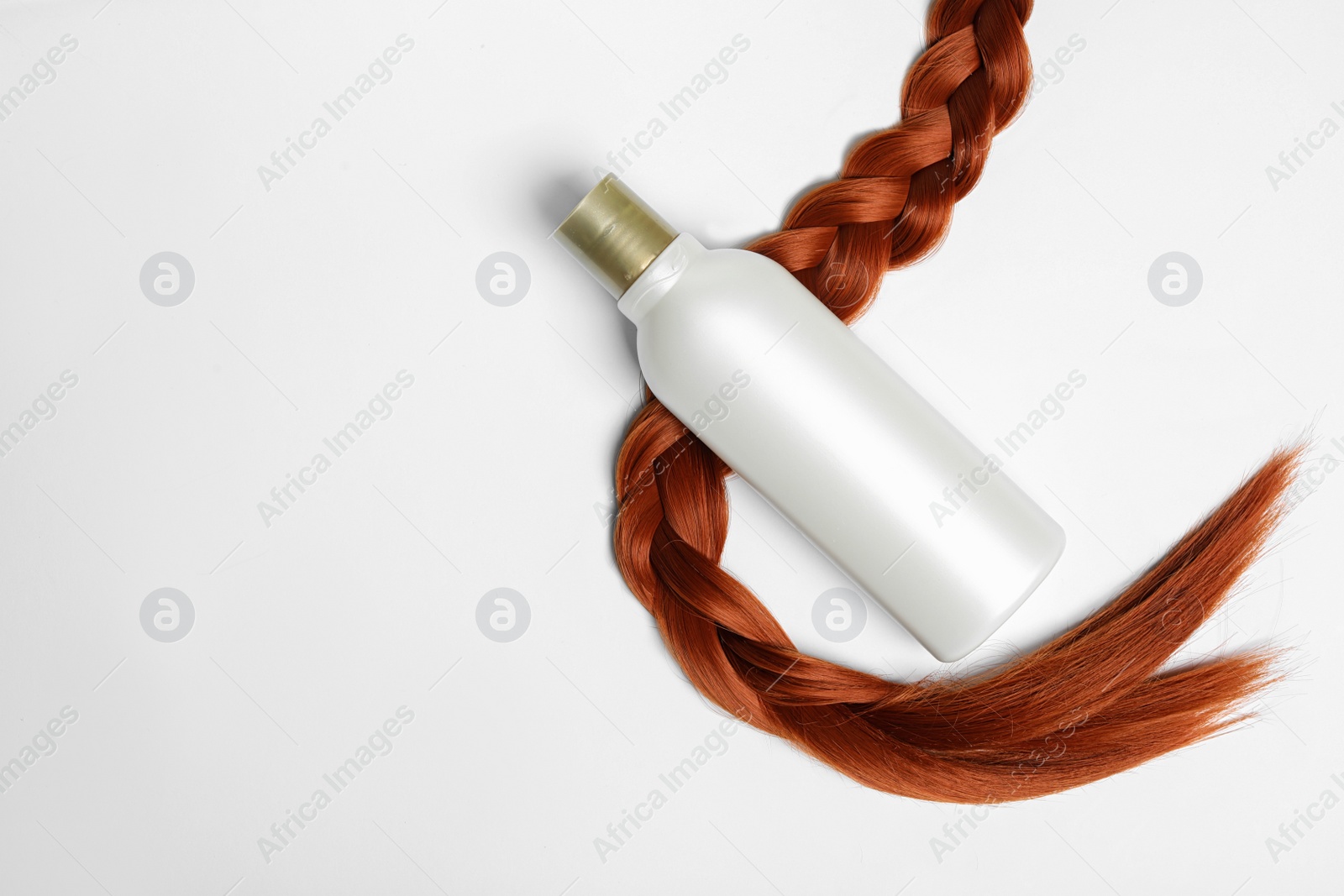 Photo of Blank bottle of cosmetic product and braided hair on white background, top view. Space for design