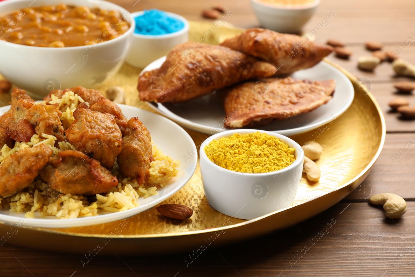 Photo of Traditional Indian food and color powder on wooden table, closeup. Holi festival celebration