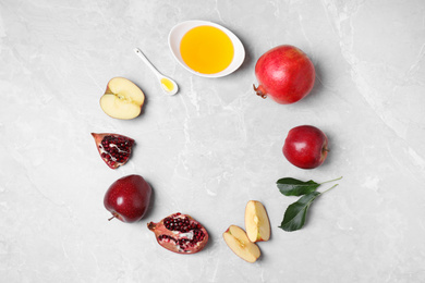 Photo of Frame of honey, apples and pomegranates on marble table, flat lay with space for text. Rosh Hashanah holiday