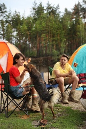 Photo of Young people having lunch with sausages near camping tents outdoors