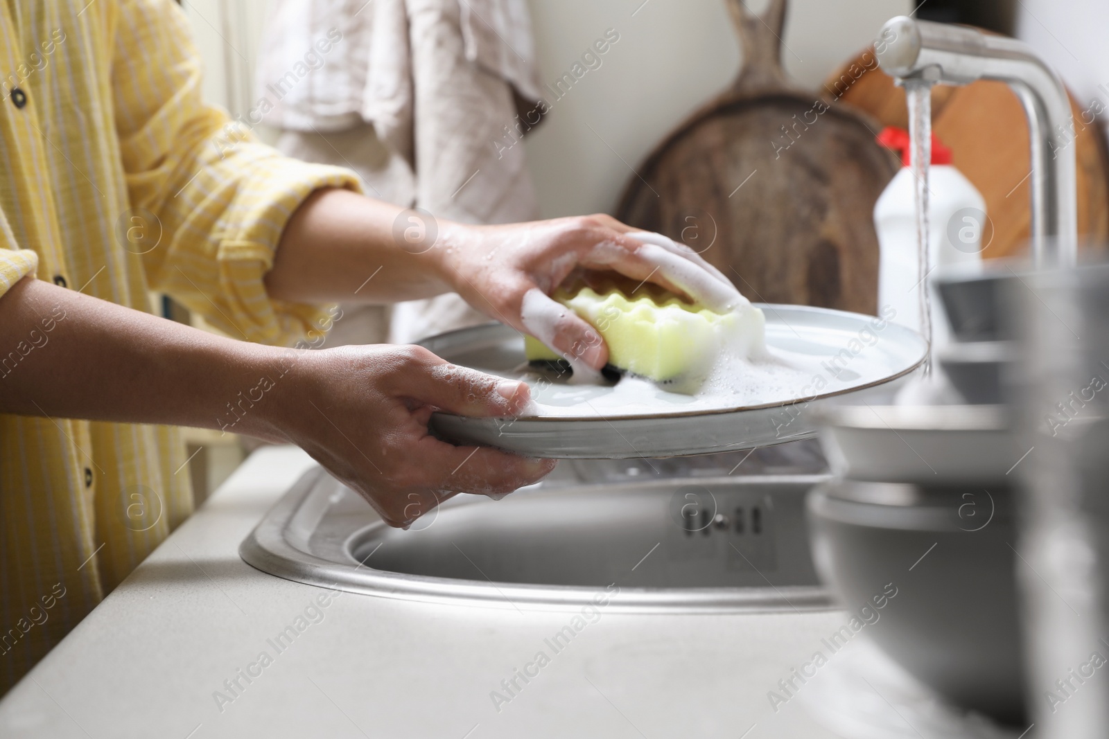 Photo of Woman washing plate in kitchen sink, closeup