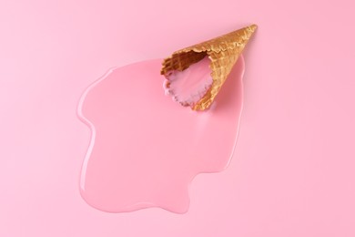 Photo of Melted ice cream and wafer cone on pink background, top view. Space for text