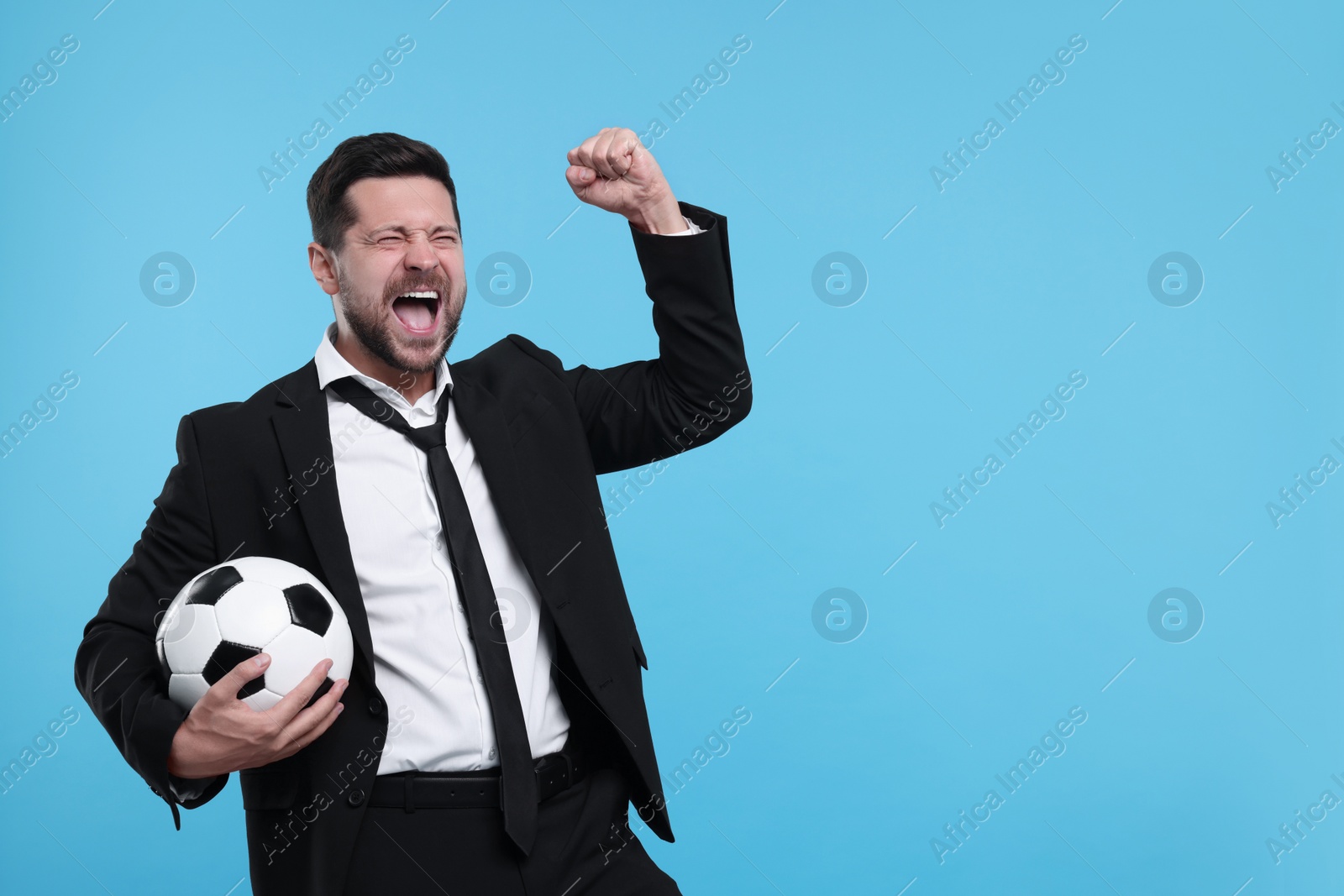 Photo of Emotional sports fan with ball celebrating on light blue background. Space for text