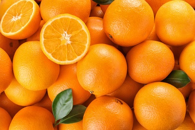 Photo of Pile of fresh ripe oranges with leaves as background, top view