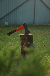 Photo of Metal axe in wooden log on backyard