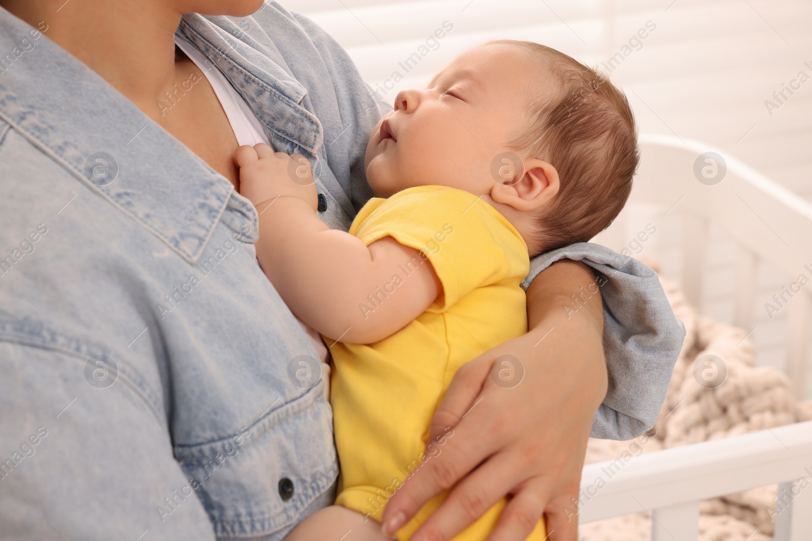 Photo of Mother holding her sleeping newborn baby at home, closeup