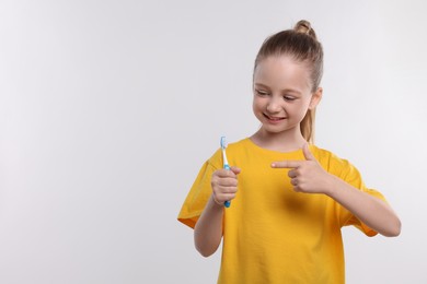 Happy girl holding toothbrush on white background. Space for text