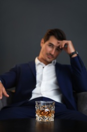 Young man with glass of whiskey indoors