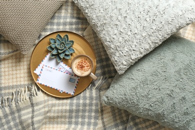 Pillows, plaid, tray with cup of coffee and letters on bed, flat lay