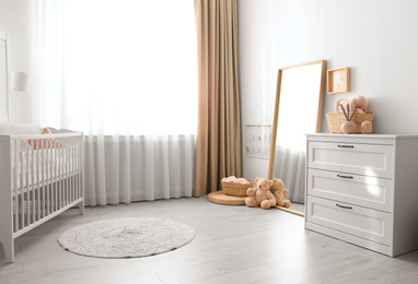Photo of Beautiful nursery interior with white chest of drawers
