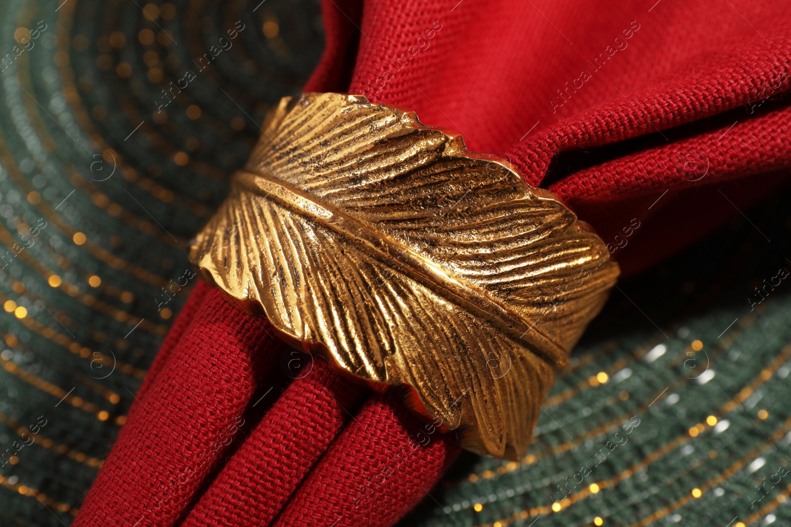 Photo of Red fabric napkin and decorative ring on serving mat, closeup