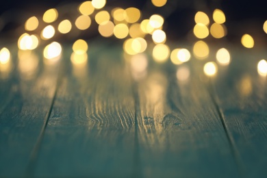 Photo of Blurred view of beautiful lights on wooden table, space for text