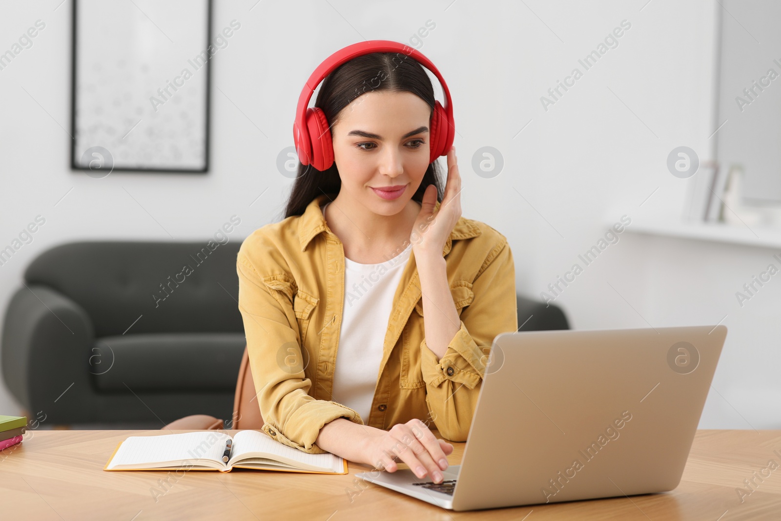 Photo of Woman in headphones studying on laptop at home. Online translation course