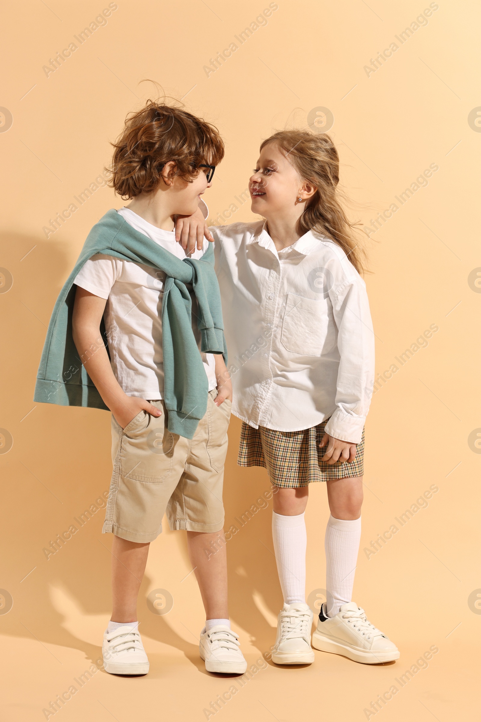 Photo of Fashion concept. Stylish children on pale orange background