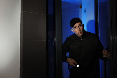 Photo of Male security guard with flashlight near entrance door at night