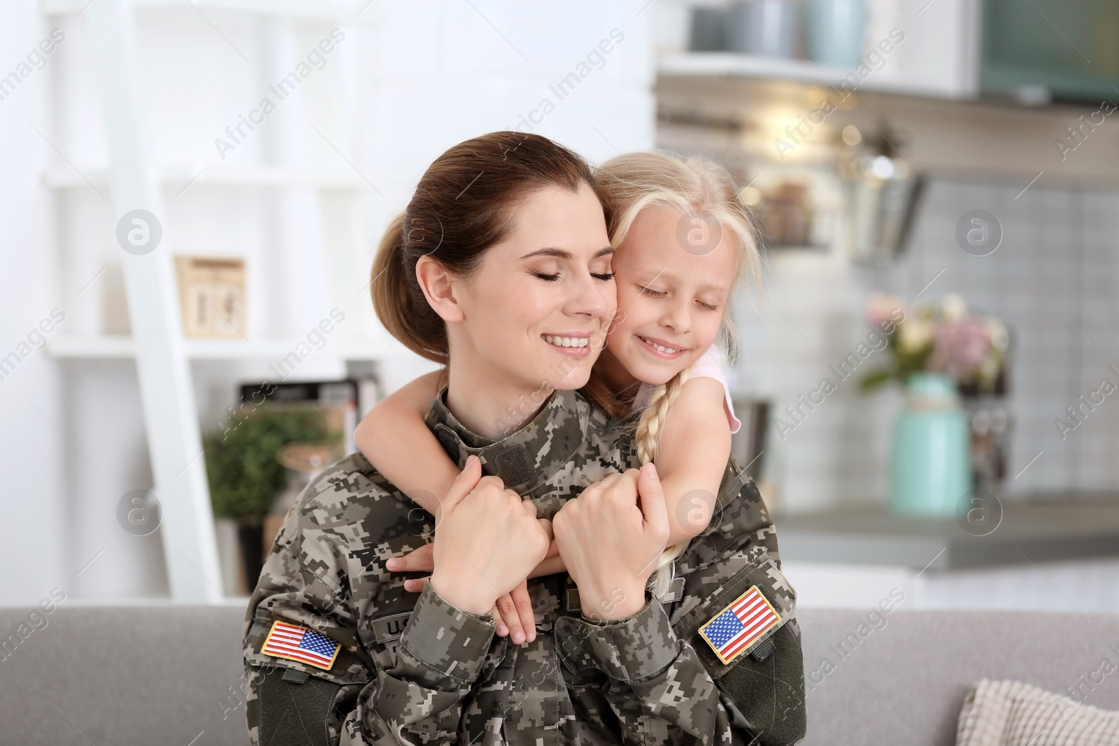 Photo of Woman in military uniform with her little daughter at home