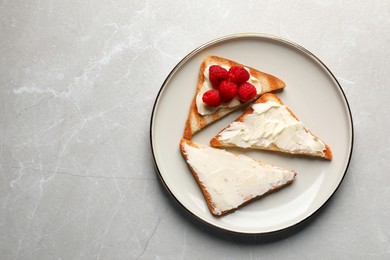 Tasty toasts with butter and raspberries on light grey marble table, top view. Space for text