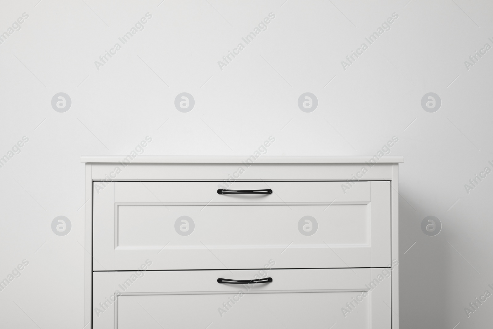 Photo of Modern wooden chest of drawers at light wall