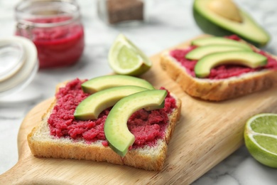 Photo of Crisp toasts with avocado and chrain on wooden board, closeup