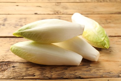 Photo of Fresh raw Belgian endives (chicory) on wooden table