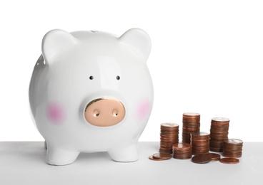 Photo of Piggy bank and different height coin stacks on white background