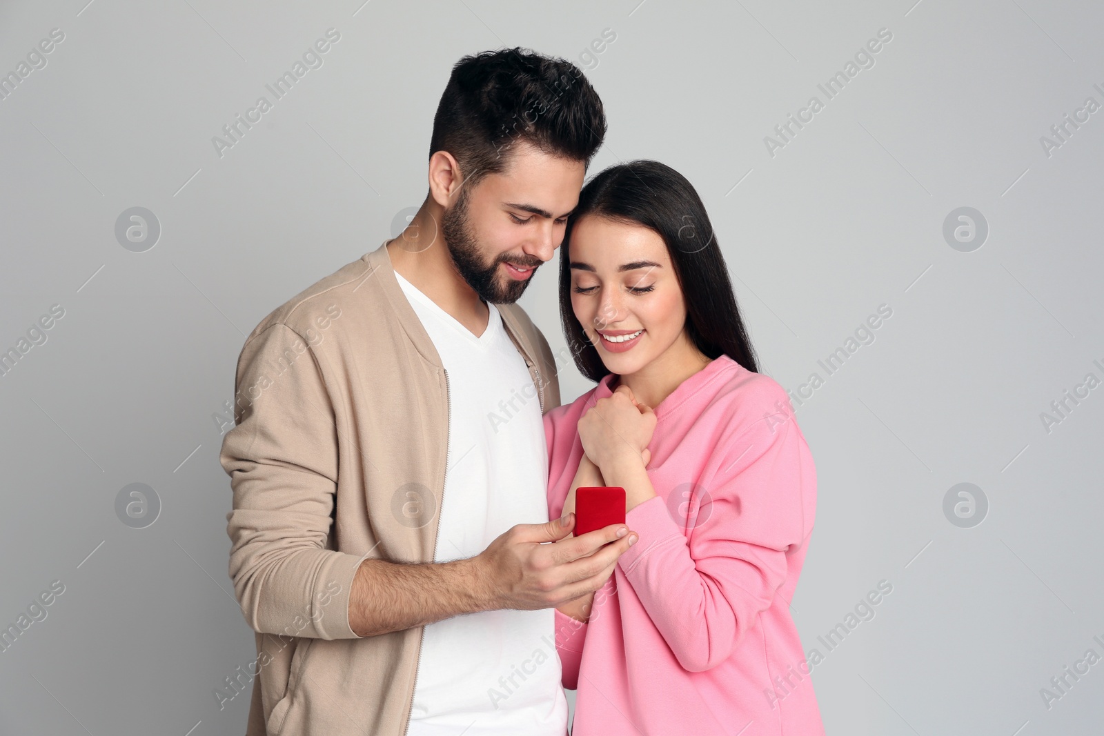 Photo of Man with engagement ring making marriage proposal to girlfriend on light grey background