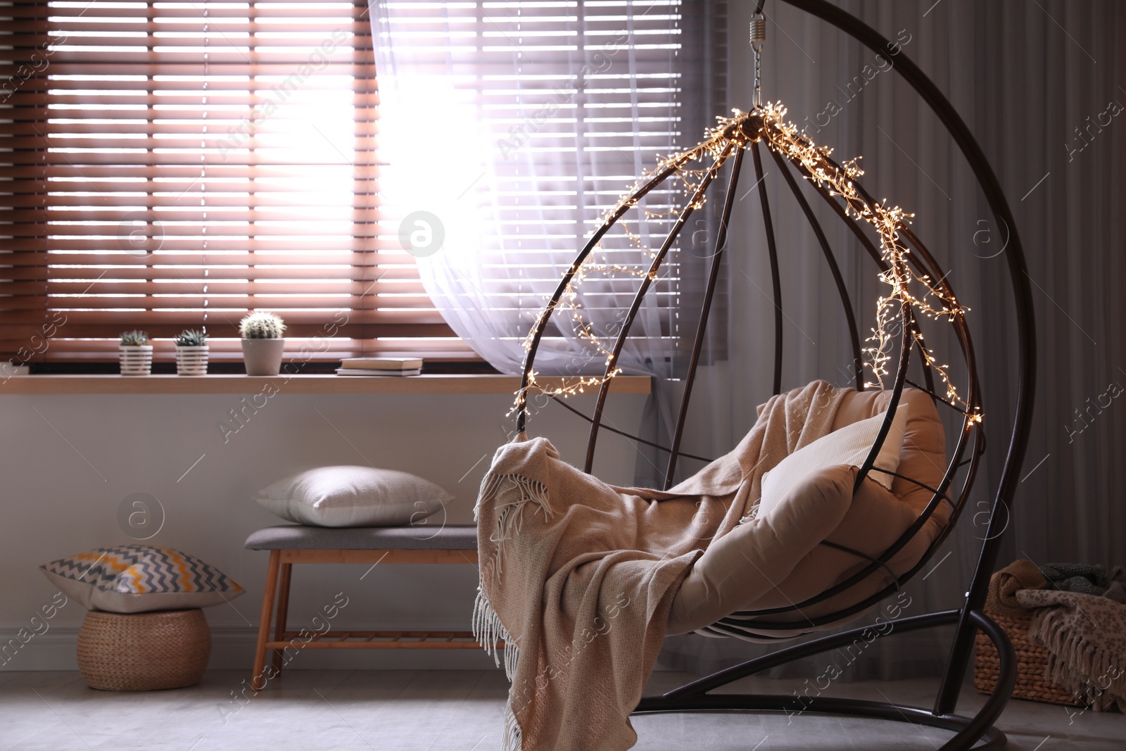 Photo of Cozy hanging chair with fairy lights in modern living room. Interior design