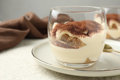 Delicious tiramisu in glass on white table, closeup. Space for text