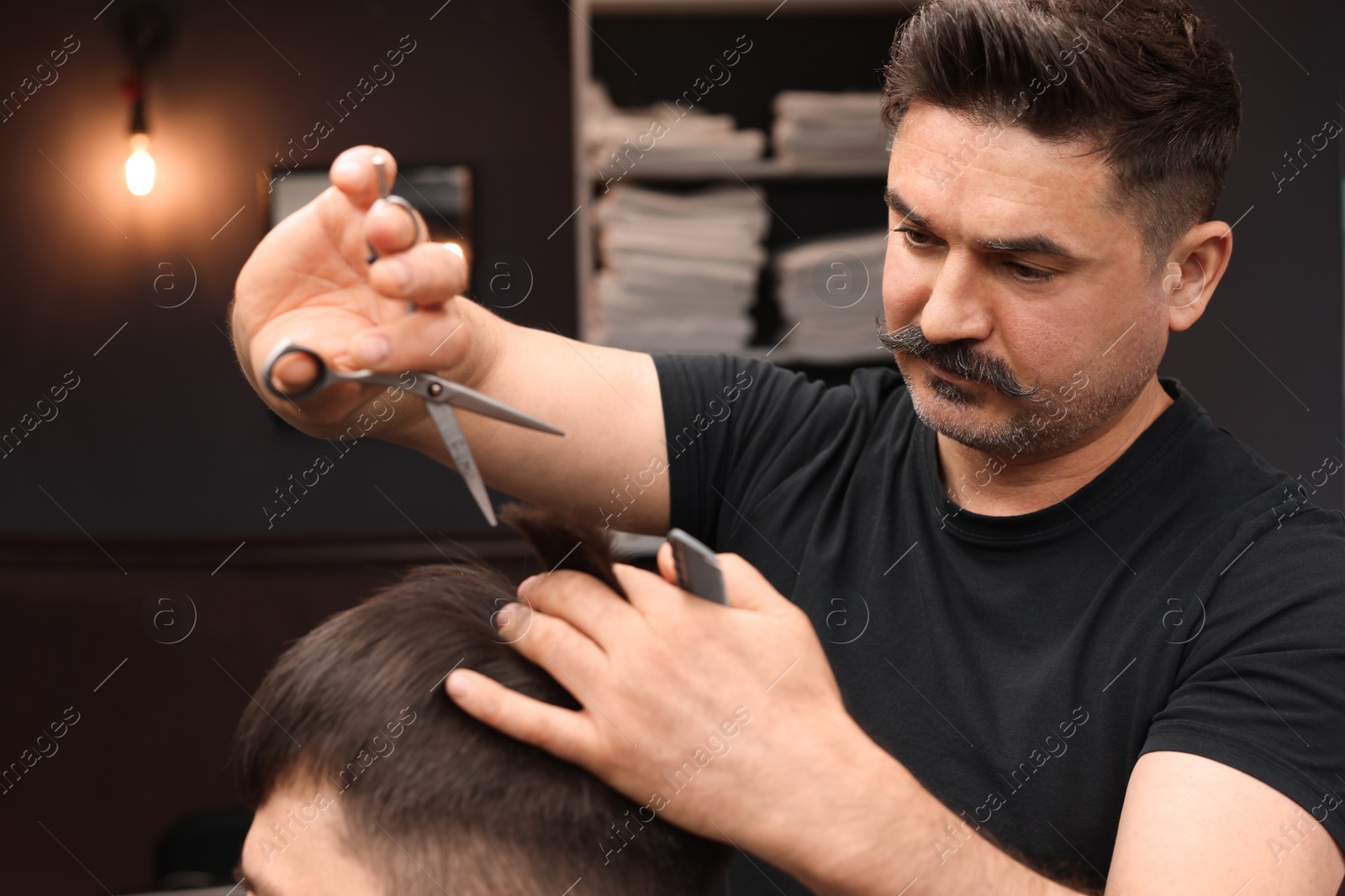 Photo of Professional hairdresser cutting man's hair in barbershop