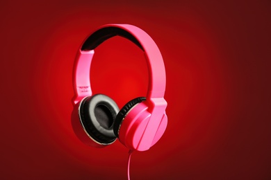 Stylish headphones with pads on color background