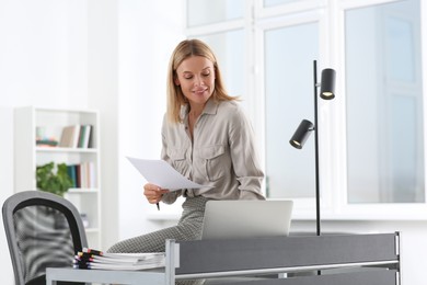 Businesswoman working with documents on grey table in office