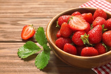 Photo of Bowl with ripe strawberries on wooden table