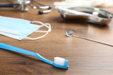 Toothbrush near dentist's tools on wooden table, closeup. Space for text