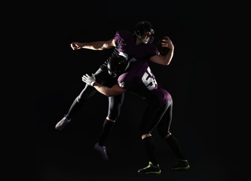 Photo of Men in uniform playing American football on dark background