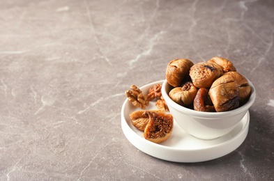 Dishware with dried figs on grey background. Space for text