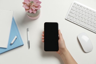 Photo of Woman with smartphone at white table, top view