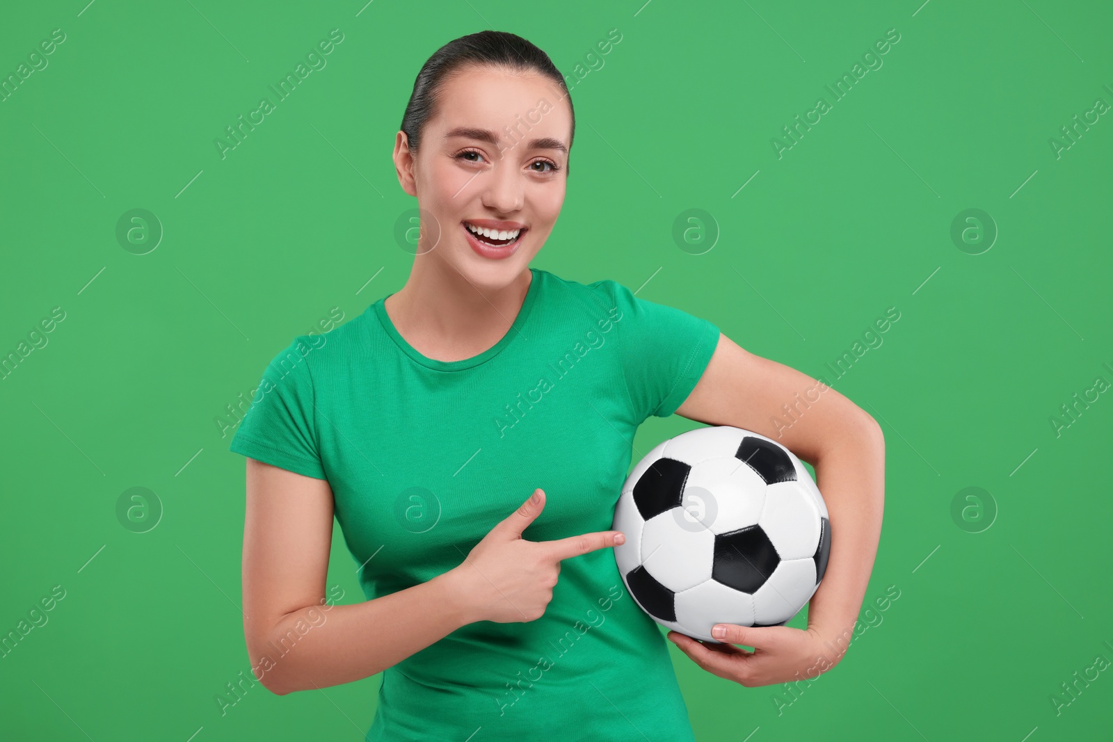 Photo of Happy fan showing soccer ball on green background