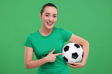 Happy fan showing soccer ball on green background