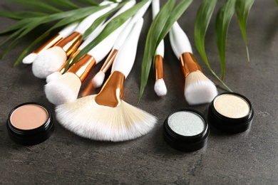 Photo of Composition with makeup brushes, cosmetic and palm leaf on grey background, closeup