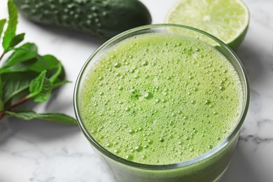 Photo of Glass with delicious detox juice and ingredients on table, closeup