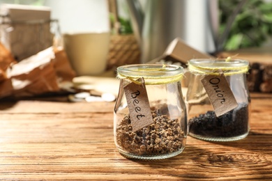 Glass jars with vegetable seeds on wooden table, space for text