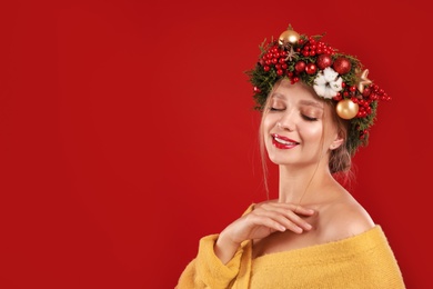 Photo of Beautiful young woman wearing Christmas wreath on red background. Space for text