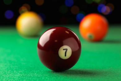 Photo of Billiard ball with number 7 on green table, closeup