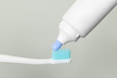 Applying paste on toothbrush against grey background