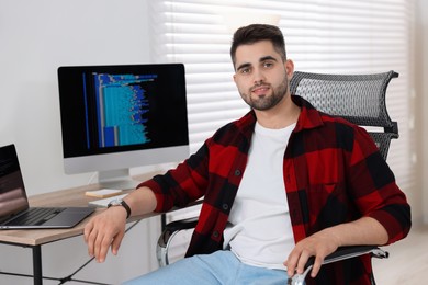 Happy young programmer working at desk in office