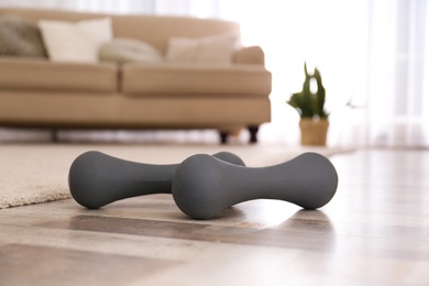 Photo of Grey dumbbells on floor in room. Home fitness