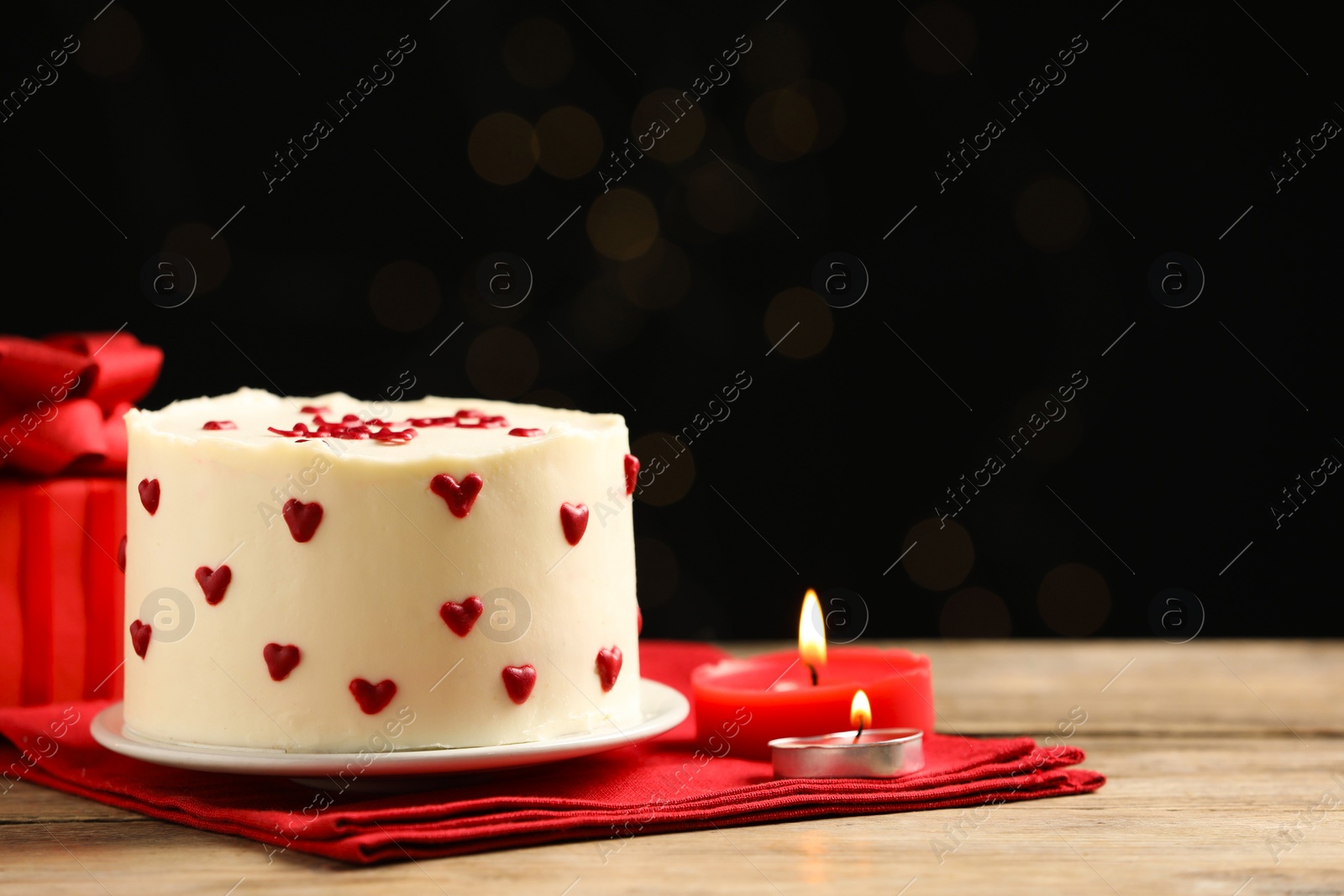 Photo of Bento cake, candles and gift box on wooden table, space for text. St. Valentine's day surprise