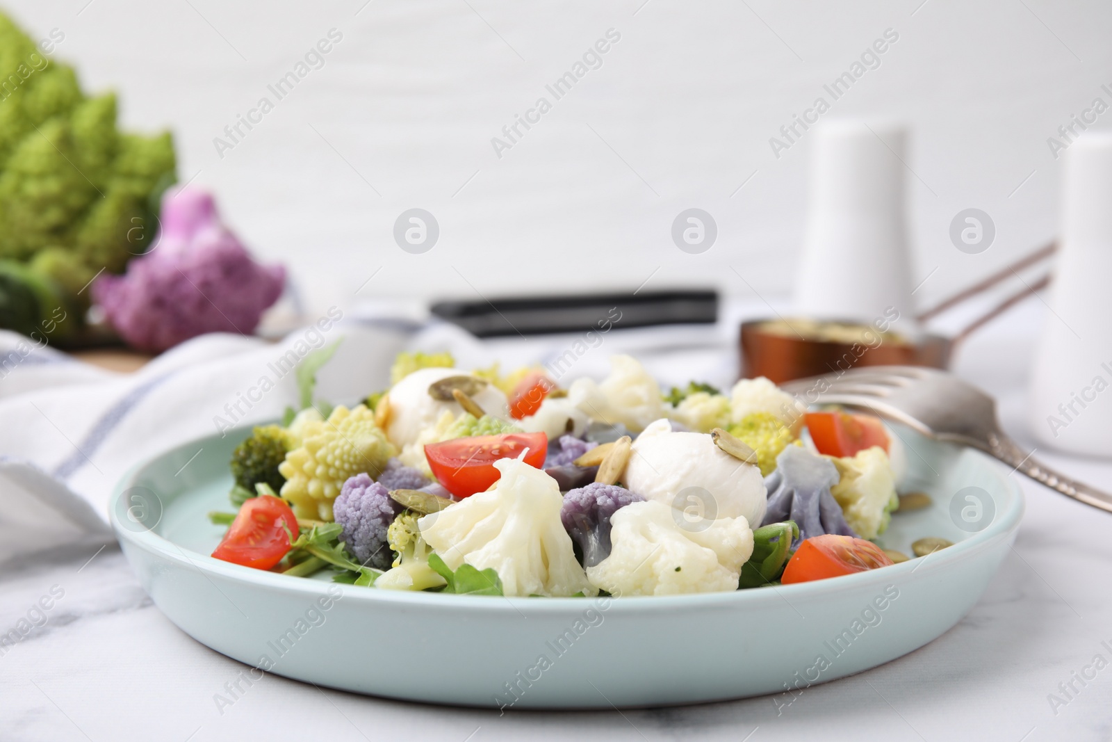 Photo of Delicious salad with cauliflower, tomato and cheese served on white marble table, closeup