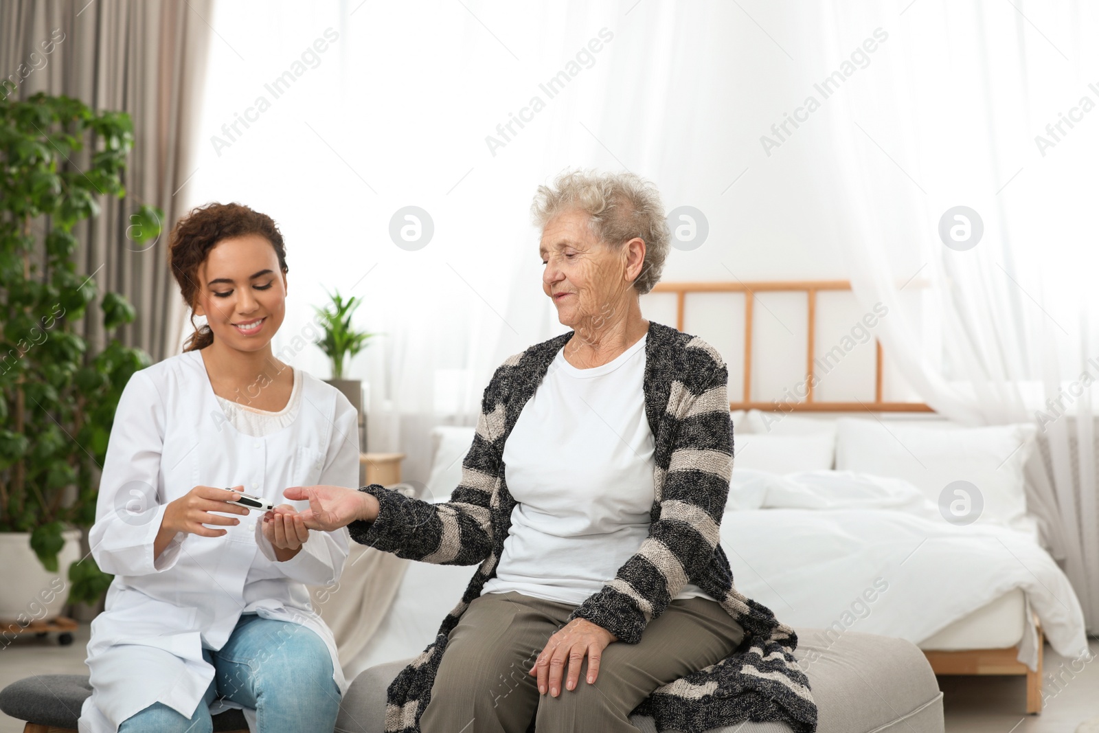 Photo of Doctor measuring patient's blood sugar level with digital glucose meter at home. Diabetes control