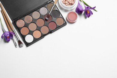 Photo of Flat lay composition with eyeshadow palette and beautiful flowers on white background, space for text